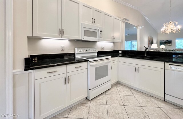 kitchen with a notable chandelier, white appliances, vaulted ceiling, and white cabinetry