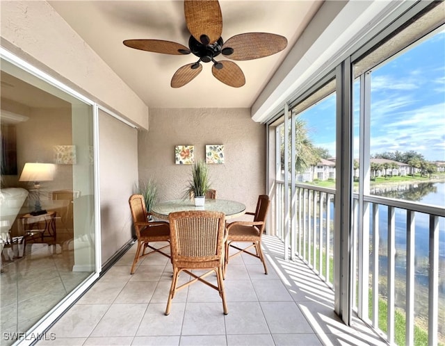 sunroom with ceiling fan and a water view