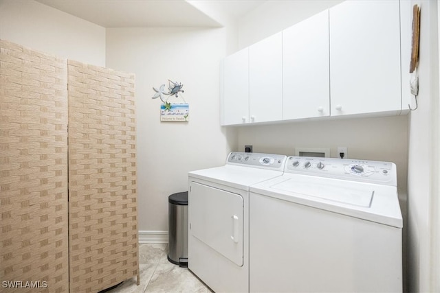 laundry room featuring cabinets, light tile patterned floors, and washing machine and clothes dryer