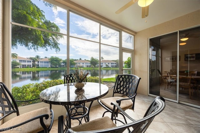 sunroom with ceiling fan and a water view