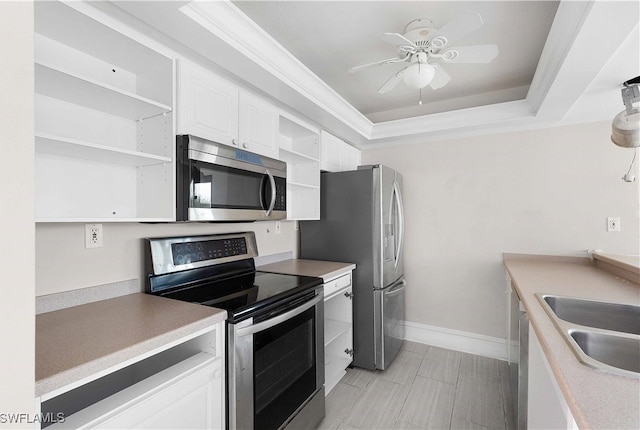 kitchen with appliances with stainless steel finishes, white cabinetry, a raised ceiling, ceiling fan, and sink