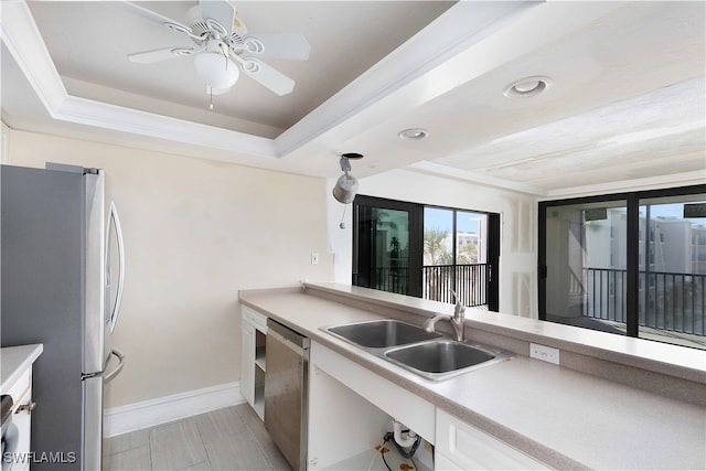 kitchen featuring appliances with stainless steel finishes, white cabinets, a tray ceiling, ceiling fan, and sink