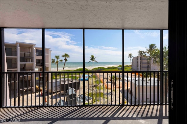 sunroom featuring a water view and a view of the beach