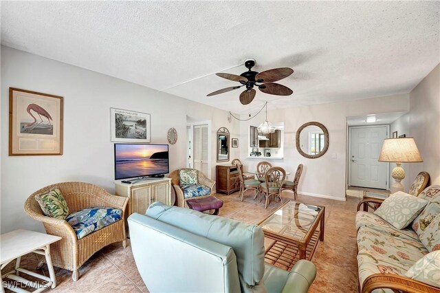 living room featuring a textured ceiling, ceiling fan with notable chandelier, and light tile patterned flooring