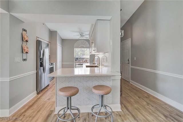 kitchen with sink, appliances with stainless steel finishes, a kitchen breakfast bar, white cabinets, and kitchen peninsula