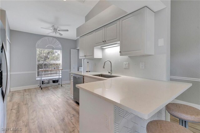 kitchen featuring sink, appliances with stainless steel finishes, white cabinets, a kitchen bar, and kitchen peninsula