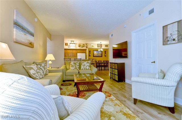 living room featuring light wood-type flooring and a textured ceiling