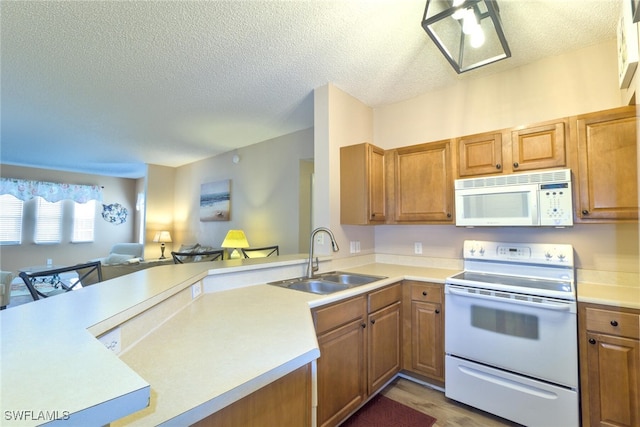 kitchen featuring white appliances, kitchen peninsula, a textured ceiling, wood-type flooring, and sink