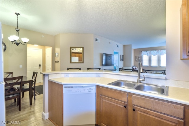 kitchen with hanging light fixtures, light hardwood / wood-style floors, white dishwasher, an inviting chandelier, and sink