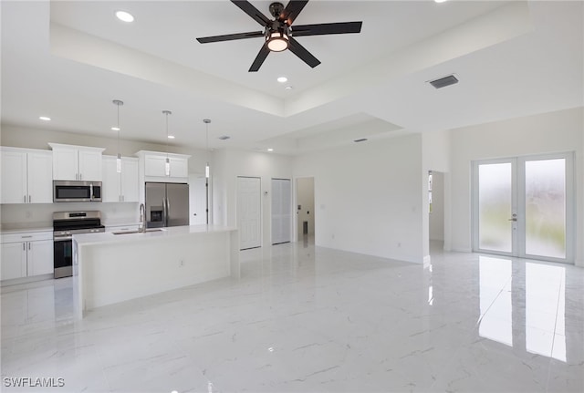 kitchen with appliances with stainless steel finishes, decorative light fixtures, an island with sink, and white cabinets