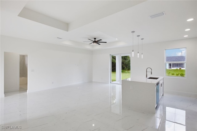 unfurnished room featuring a tray ceiling, ceiling fan, and sink