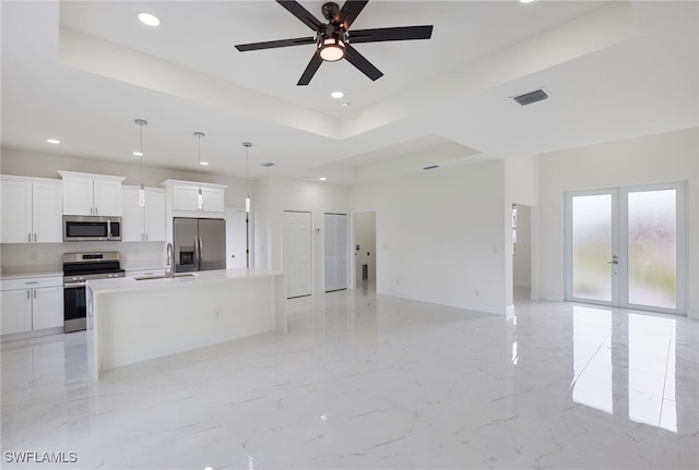 kitchen with a kitchen island with sink, white cabinets, hanging light fixtures, stainless steel appliances, and ceiling fan