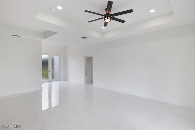 spare room with a tray ceiling, ceiling fan, and french doors