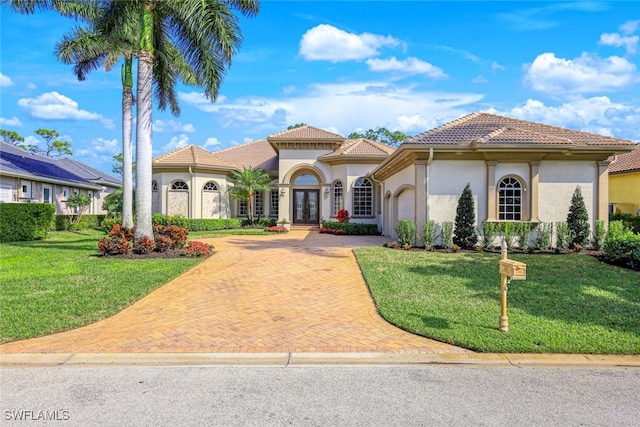 mediterranean / spanish-style house featuring a garage, french doors, and a front lawn