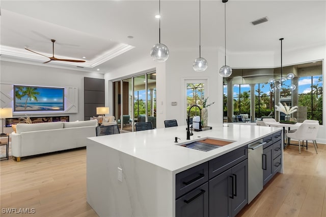 kitchen with a center island with sink, light hardwood / wood-style floors, sink, and hanging light fixtures