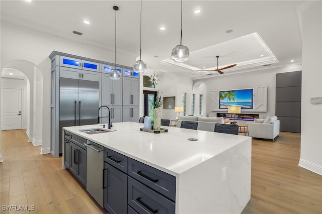 kitchen featuring a kitchen island with sink, sink, light hardwood / wood-style floors, and decorative light fixtures