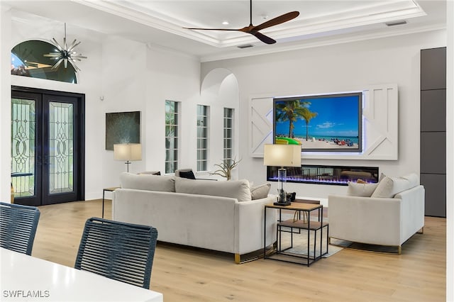 living room featuring a raised ceiling, light hardwood / wood-style flooring, and crown molding