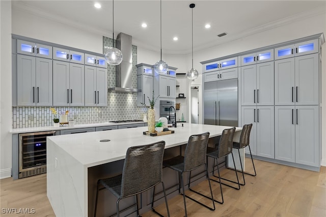 kitchen featuring decorative light fixtures, a spacious island, wall chimney range hood, and stainless steel appliances