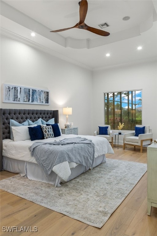 bedroom with wood-type flooring, a raised ceiling, and ceiling fan