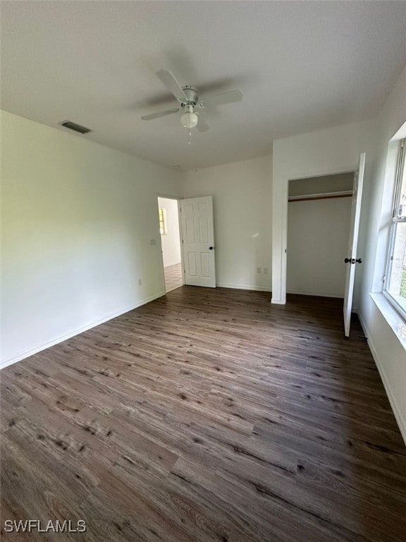 unfurnished bedroom with dark hardwood / wood-style flooring, ceiling fan, and a closet