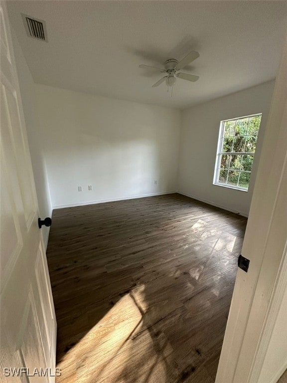 empty room with ceiling fan and dark wood-type flooring