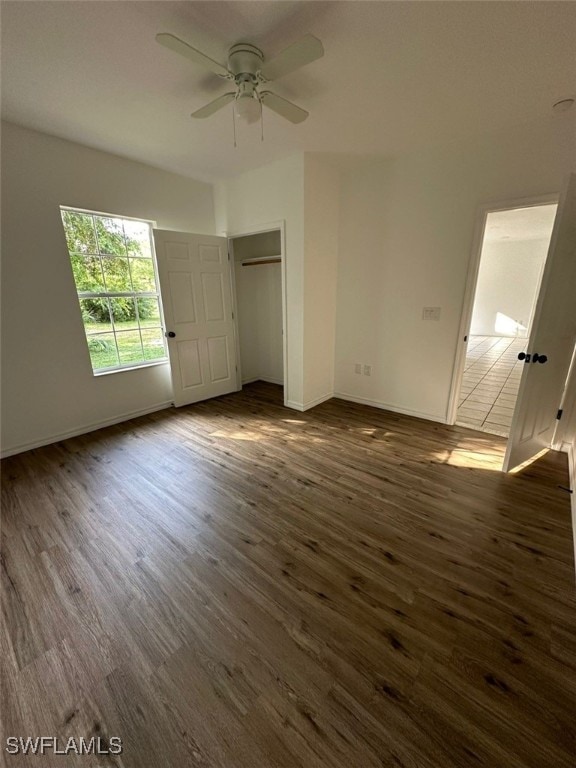 unfurnished bedroom featuring dark hardwood / wood-style flooring, ceiling fan, and a closet