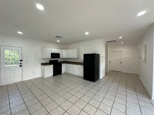 kitchen featuring light tile patterned floors, white cabinets, sink, and black appliances