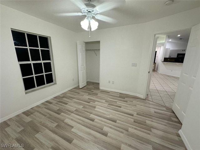 unfurnished bedroom with light wood-type flooring, ceiling fan, and a closet