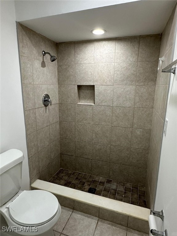 bathroom with tile patterned floors, toilet, and tiled shower