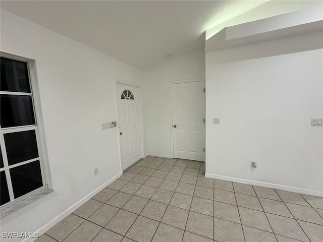 tiled spare room featuring lofted ceiling