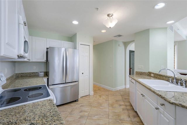 kitchen with light stone countertops, white appliances, white cabinetry, and sink