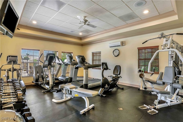 gym featuring ceiling fan, an AC wall unit, a tray ceiling, a paneled ceiling, and ornamental molding