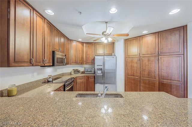 kitchen featuring light stone countertops, appliances with stainless steel finishes, ceiling fan, and sink