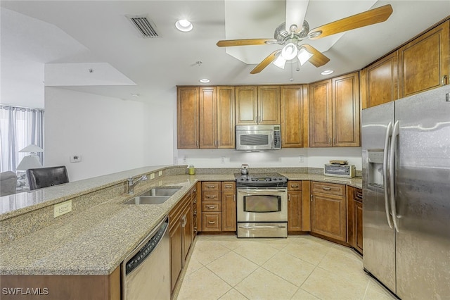 kitchen featuring light stone counters, kitchen peninsula, sink, and appliances with stainless steel finishes