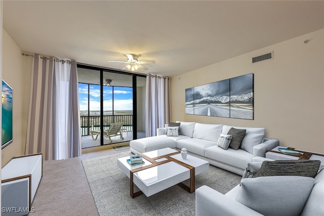 living room featuring ceiling fan, floor to ceiling windows, and light carpet