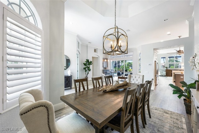 dining room with light hardwood / wood-style floors, ornamental molding, and ceiling fan with notable chandelier