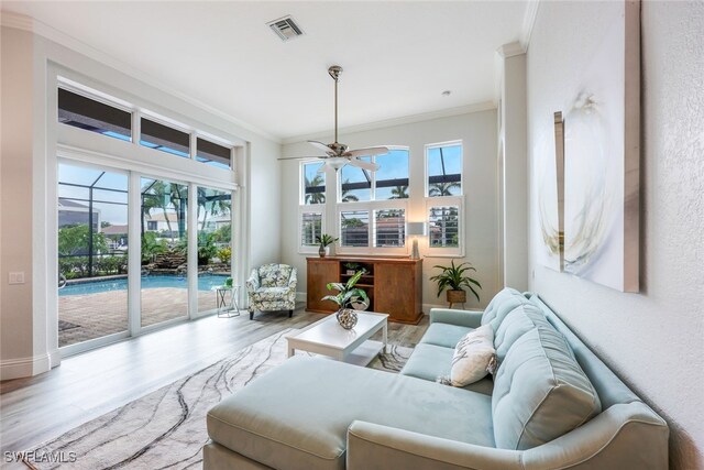 living room with ceiling fan, crown molding, and light hardwood / wood-style flooring