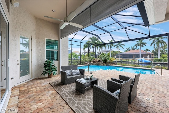 view of swimming pool with an outdoor living space, ceiling fan, a patio, and a lanai