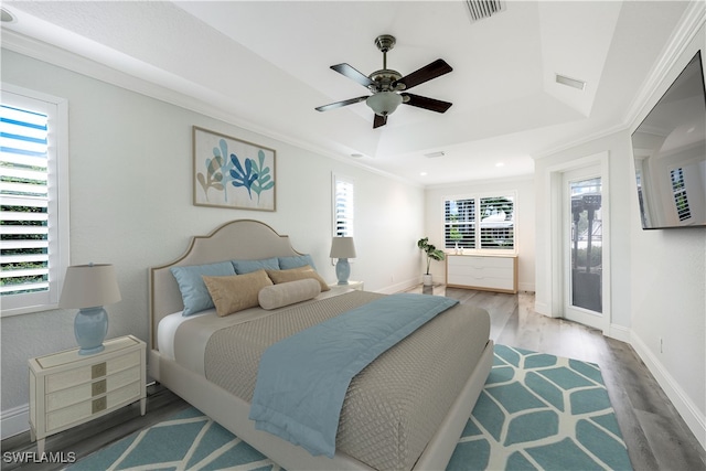 bedroom featuring ceiling fan, crown molding, multiple windows, and hardwood / wood-style floors