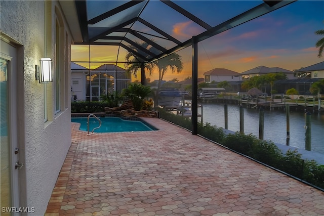 pool at dusk with a patio, a lanai, and a water view