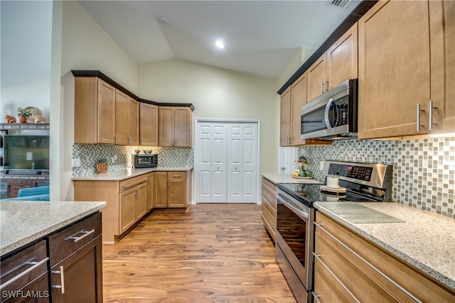 kitchen with tasteful backsplash, lofted ceiling, light hardwood / wood-style flooring, appliances with stainless steel finishes, and light stone countertops