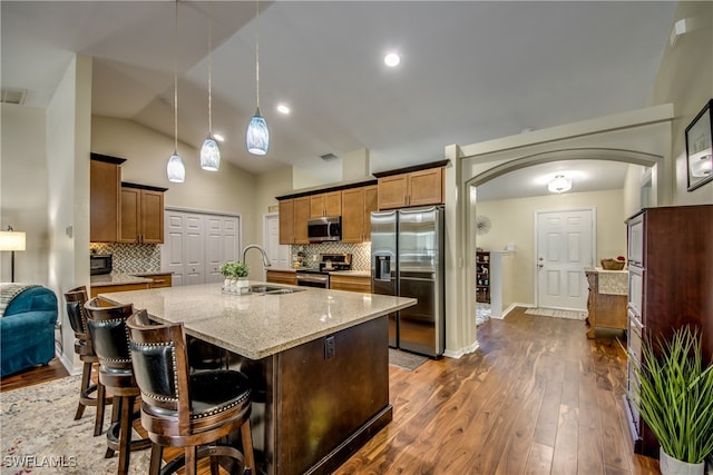 kitchen featuring decorative backsplash, stainless steel appliances, hanging light fixtures, and dark wood-type flooring