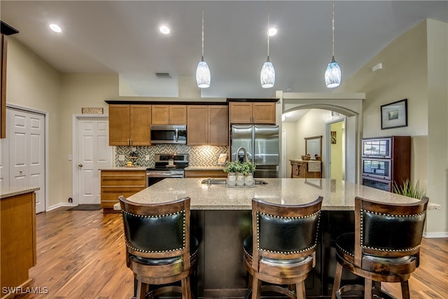 kitchen featuring wood-type flooring, decorative light fixtures, and stainless steel appliances