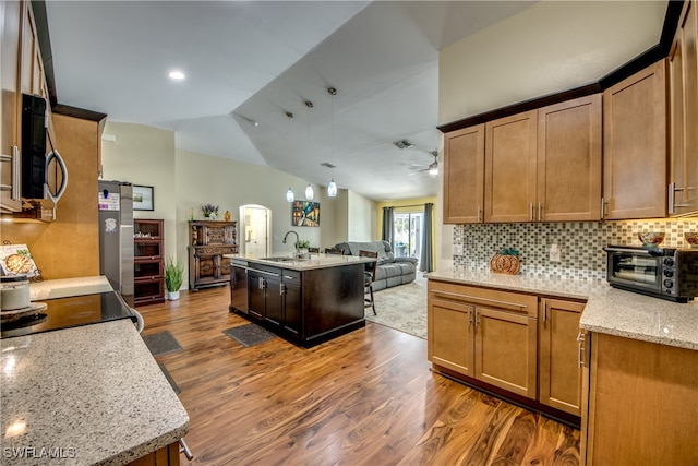 kitchen featuring light stone countertops, lofted ceiling, ceiling fan, a kitchen island with sink, and dark hardwood / wood-style floors