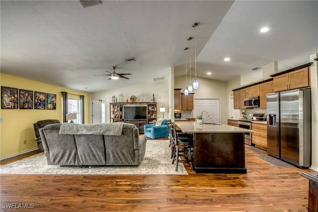 kitchen featuring hardwood / wood-style flooring, vaulted ceiling, hanging light fixtures, appliances with stainless steel finishes, and ceiling fan