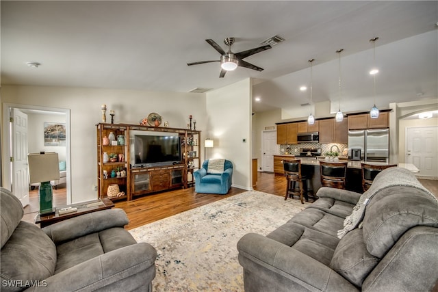 living room with wood-type flooring, vaulted ceiling, and ceiling fan