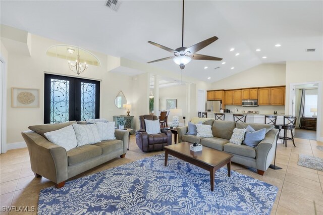 tiled living room with french doors, ceiling fan with notable chandelier, and lofted ceiling