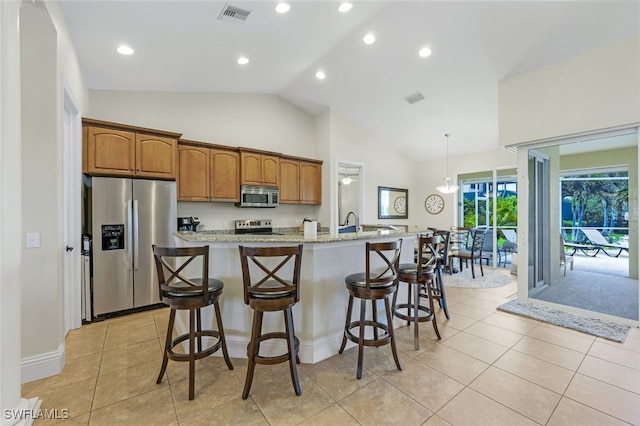 kitchen with light stone countertops, a center island with sink, stainless steel appliances, and a kitchen bar