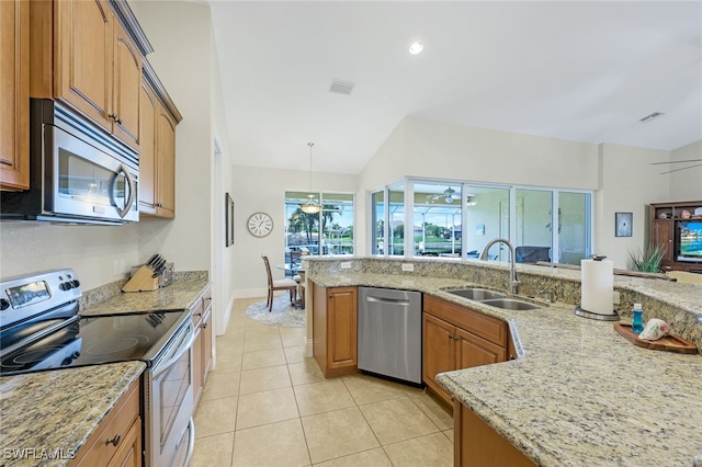 kitchen with light stone counters, sink, vaulted ceiling, stainless steel appliances, and decorative light fixtures