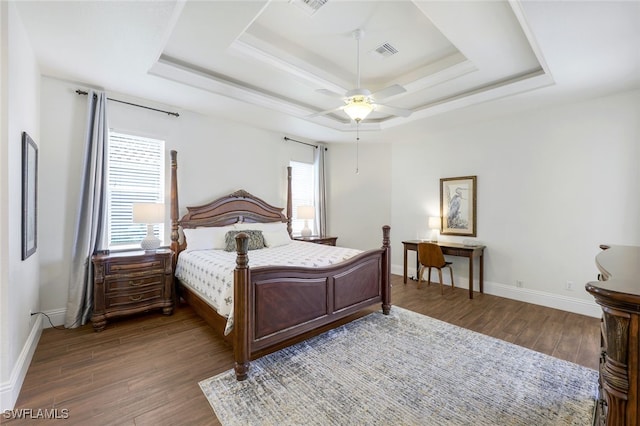 bedroom featuring a tray ceiling, multiple windows, and dark hardwood / wood-style flooring